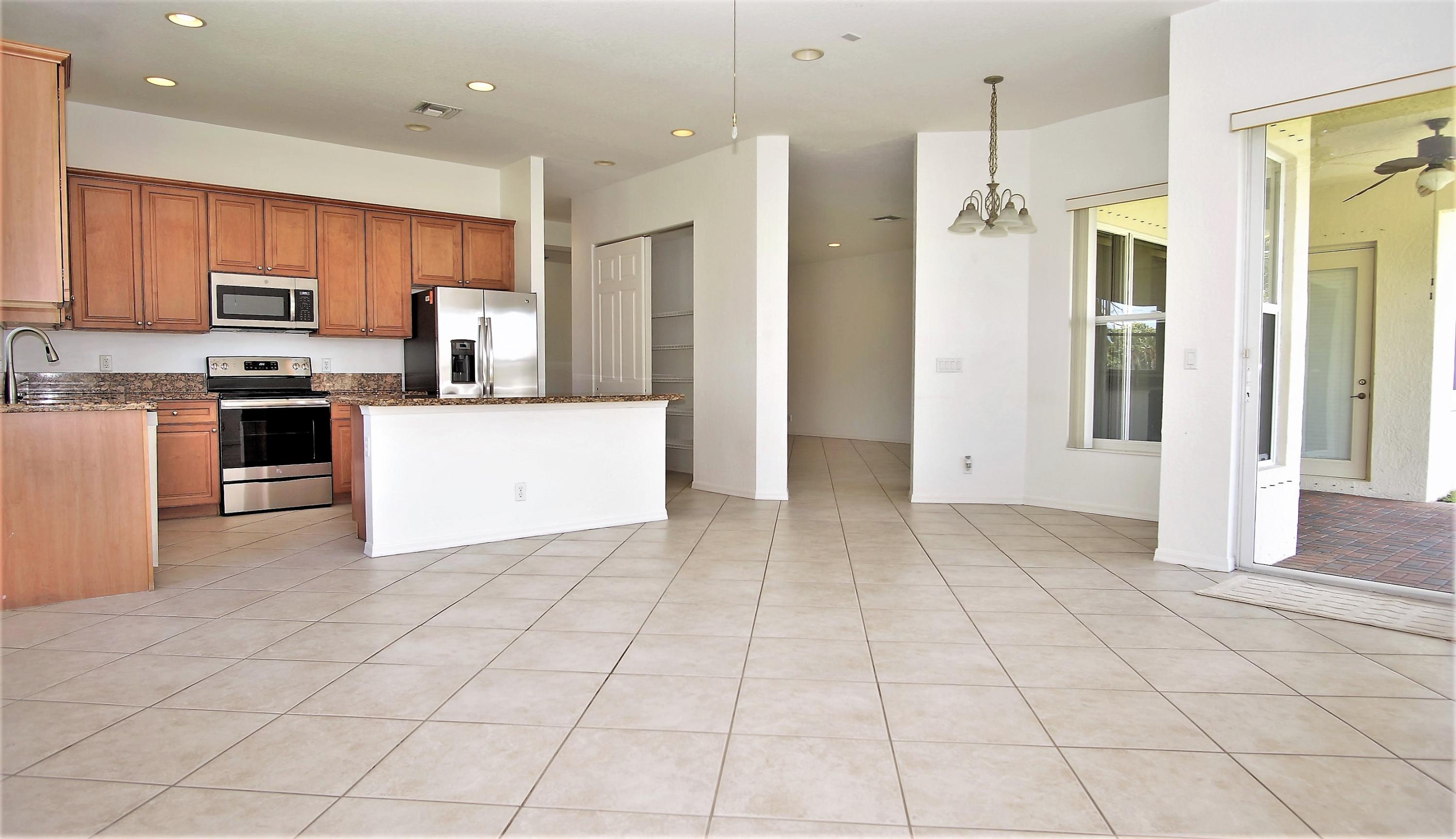 4688 Manderly Drive Wellington, FL 33449 - Photo 9 of 55 a large white kitchen with stainless steel appliances granite countertop a refrigerator and a stove top oven