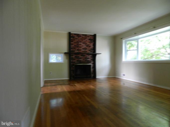 3513 Greenly Street Silver Spring, MD 20906 - Photo 5 of 12 an empty room with wooden floor fireplace and windows