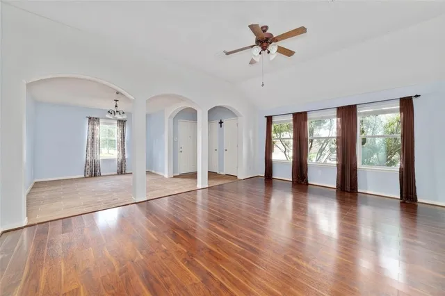 a view of an empty room with window and wooden floor