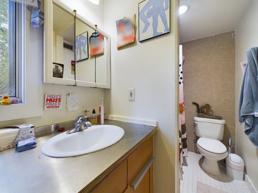 915 Keith Lane, Unit 103 Austin, TX 78705 - Photo 12 of 17 a bathroom with a sink toilet and a mirror