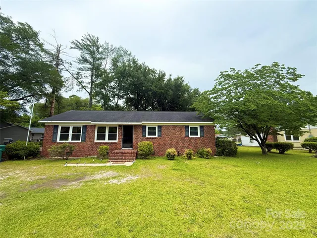 a front view of house with yard and trees around