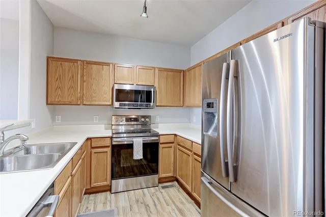 a kitchen with stainless steel appliances granite countertop a refrigerator a sink dishwasher a stove top oven a counter space and cabinets