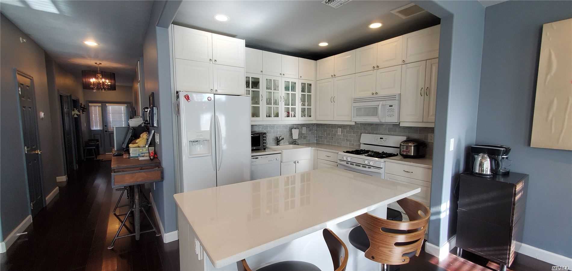 a kitchen with a refrigerator a stove top oven a sink dishwasher and white cabinets with wooden floor