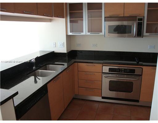 31 Southeast 5th Street, Unit 1210 Miami, FL 33131 - Photo 7 of 26 a kitchen with granite countertop a stove and a microwave