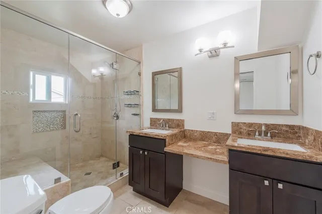 a bathroom with a granite countertop sink toilet a mirror a shower and vanity