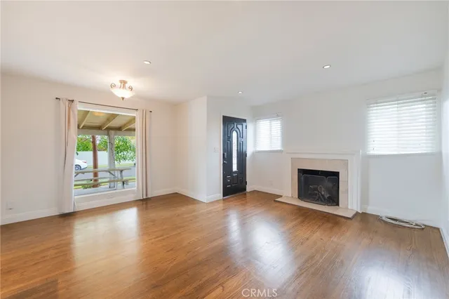 an empty room with wooden floor fireplace and windows