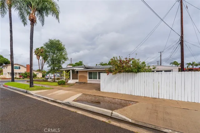 a view of a house with palm trees next to a road