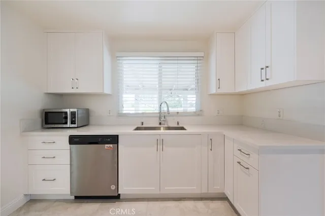 a kitchen with white cabinets appliances a sink and a window