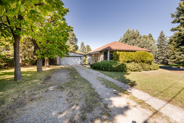 3959 Main Street Logan, UT 84321 - Photo 5 of 35 Gravel driveway leading to a detached garage and a single-story home with a hip roof and established perimeter landscaping