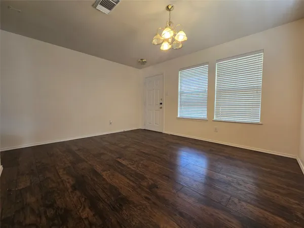 an empty room with wooden floor and window