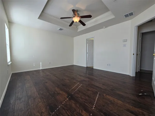 an empty room with wooden floor ceiling fan and window