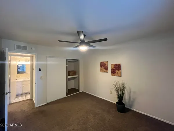 a view of a livingroom with a ceiling fan & windows