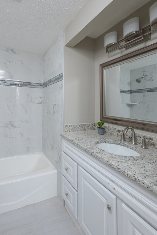 299 Center Street Randolph, MA 02368 - Photo 17 of 32 a bathroom with a granite countertop bathtub sink vanity and mirror
