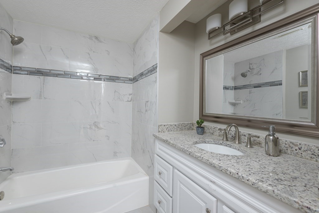 299 Center Street Randolph, MA 02368 - Photo 18 of 32 a bathroom with a granite countertop bathtub shower sink vanity and mirror