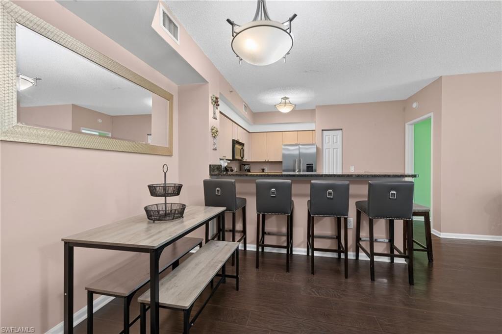 1105 Reserve Court, Unit 206 Naples, FL 34105 - Photo 3 of 23 a kitchen with stainless steel appliances granite countertop a dining table chairs and chandelier