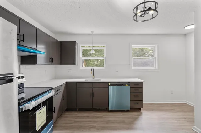 a kitchen with stainless steel appliances granite countertop a sink cabinets a stove and a refrigerator