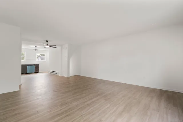 a view of empty room with wooden floor and kitchen