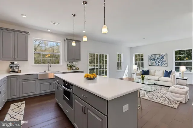 a kitchen with a stove a sink and living room view