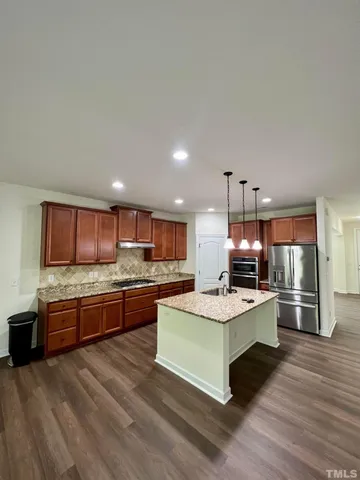 a large kitchen with stainless steel appliances kitchen island granite countertop a stove and a refrigerator