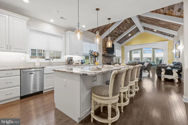 a kitchen with stainless steel appliances granite countertop a refrigerator a oven a stove and a dining table with wooden floor