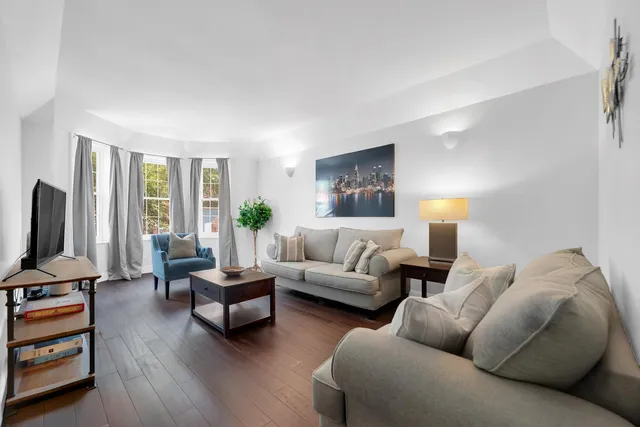 a living room with furniture flat screen tv and a large window
