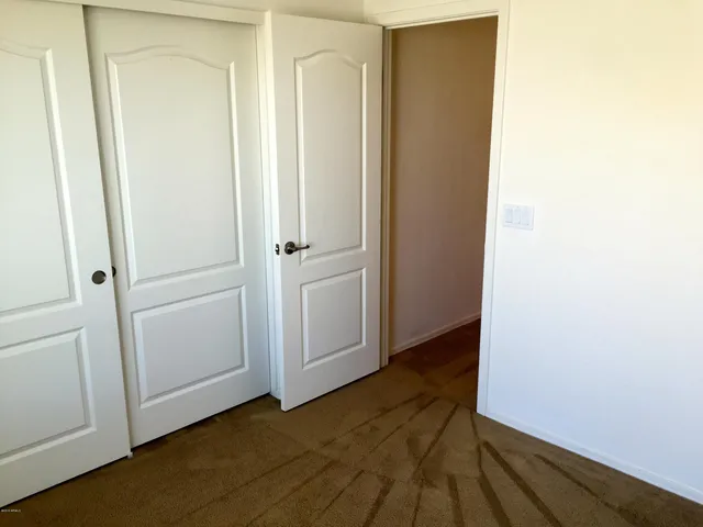 a view of an empty room with closet and wooden floor