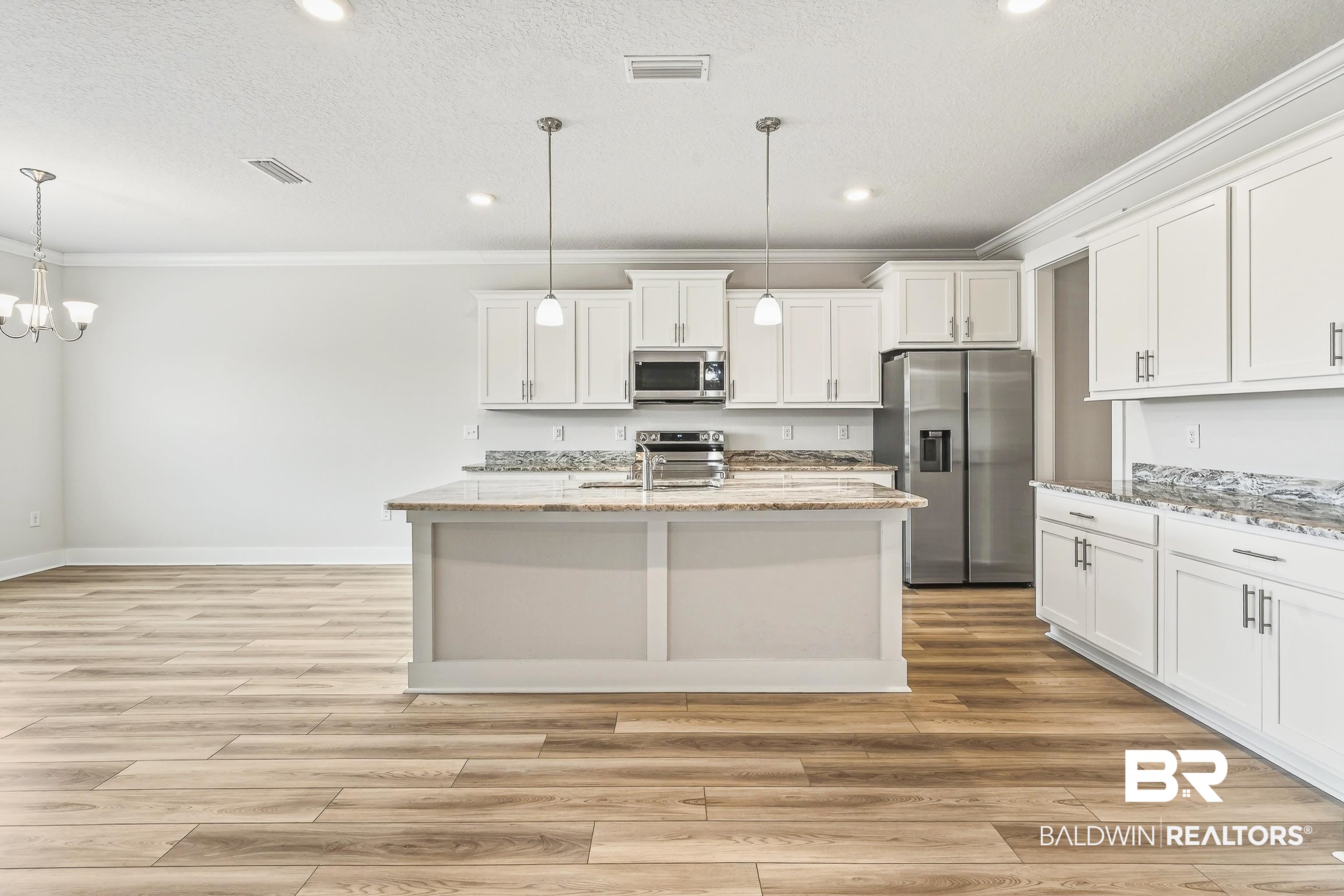 1728 Partridge Street Foley, AL 36535 - Photo 10 of 37 Kitchen with stainless steel appliances, white cabinets, light stone countertops, a kitchen island with sink, and light wood-style floors