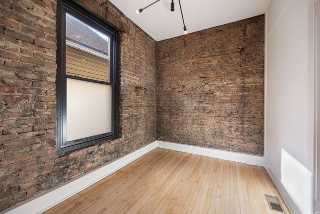 a view of a room with wooden floor and brick walls