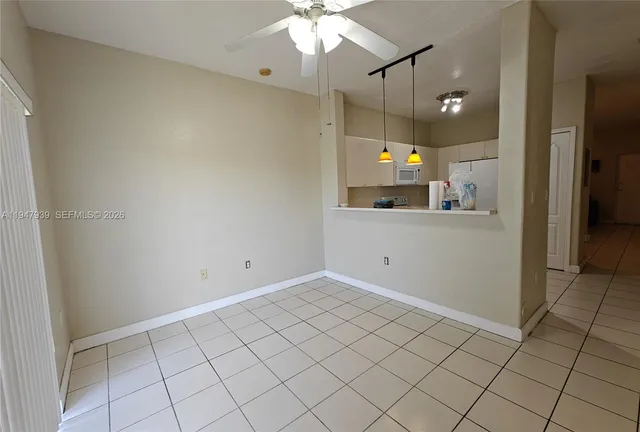 an empty room with kitchen and a chandelier fan