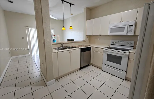 a kitchen with granite countertop a stove a sink and a refrigerator
