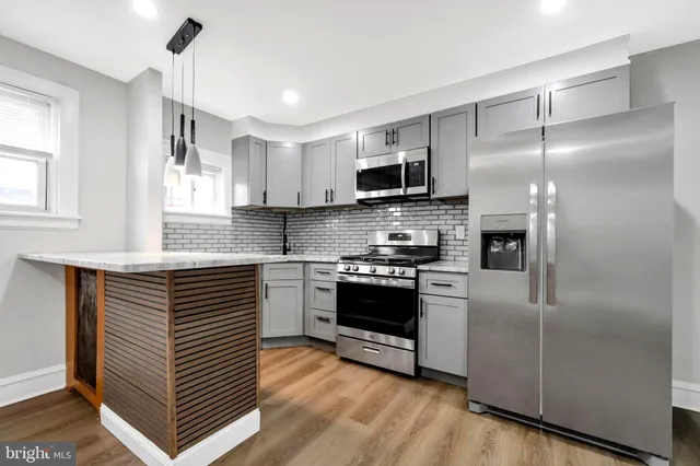 a kitchen with kitchen island granite countertop a refrigerator and a stove top oven