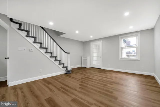a view of an empty room with wooden floor and stairs