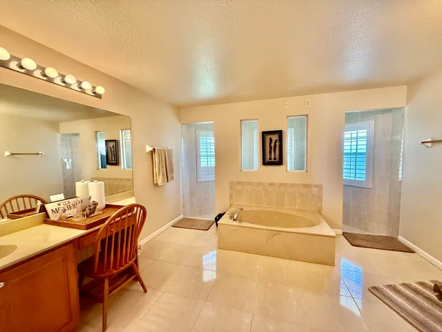 a spacious bathroom with a tub a sink and mirror