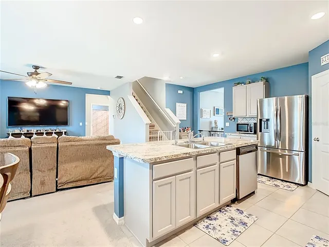 a living room with stainless steel appliances kitchen island granite countertop a stove and a flat screen tv
