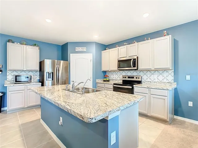 a kitchen with granite countertop a sink stove and refrigerator
