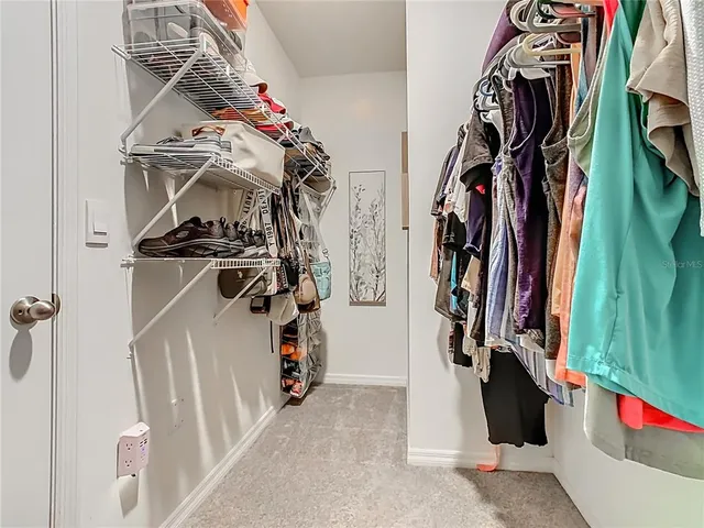a view of walk in closet with clothes and shoes