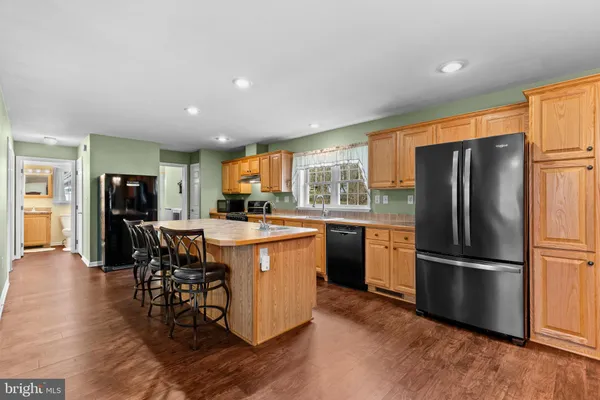 a kitchen with stainless steel appliances granite countertop a refrigerator a stove a sink a dining table and chairs with wooden floor