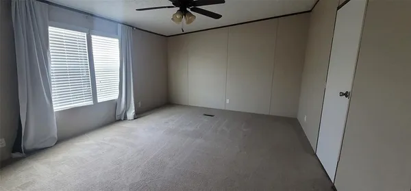 an empty room with a window and a fan