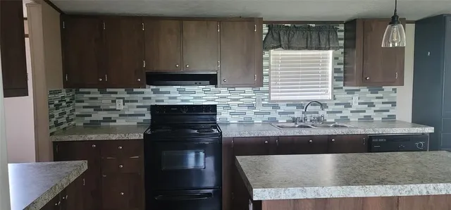 a kitchen with kitchen island granite countertop a sink and a stove