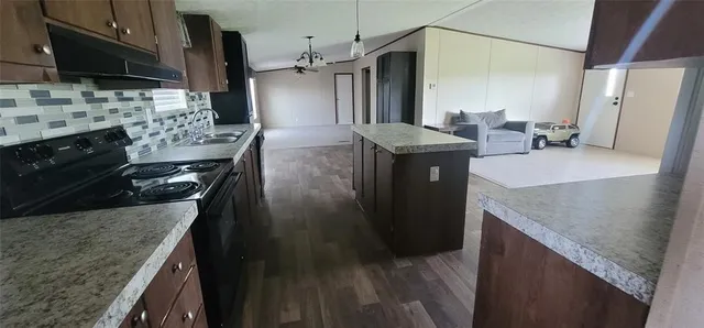 a kitchen with stainless steel appliances granite countertop a sink a stove and a refrigerator