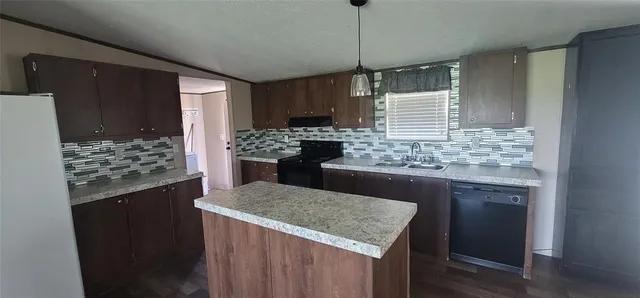 a kitchen with kitchen island granite countertop a sink stove and refrigerator