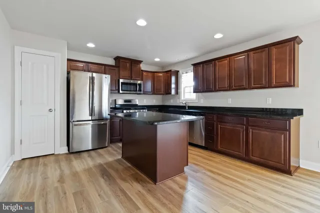 a kitchen with stainless steel appliances granite countertop a stove a refrigerator and a sink with wooden cabinets