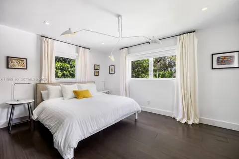 a bedroom with a bed a mirror and a large window