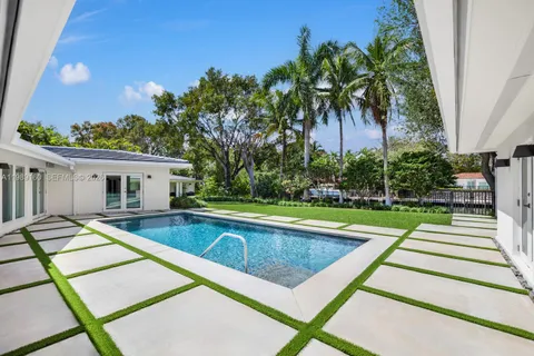 a view of swimming pool with a yard and palm trees