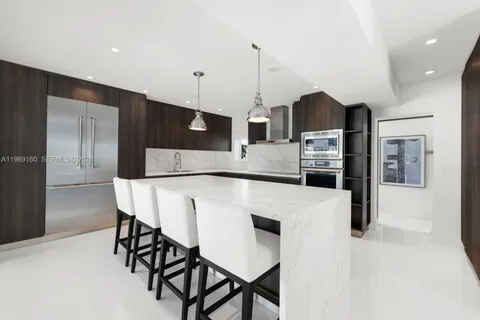 a kitchen with stainless steel appliances kitchen island granite countertop a table chairs and a refrigerator