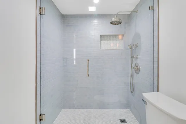 a bathroom with a toilet a sink a mirror and shower