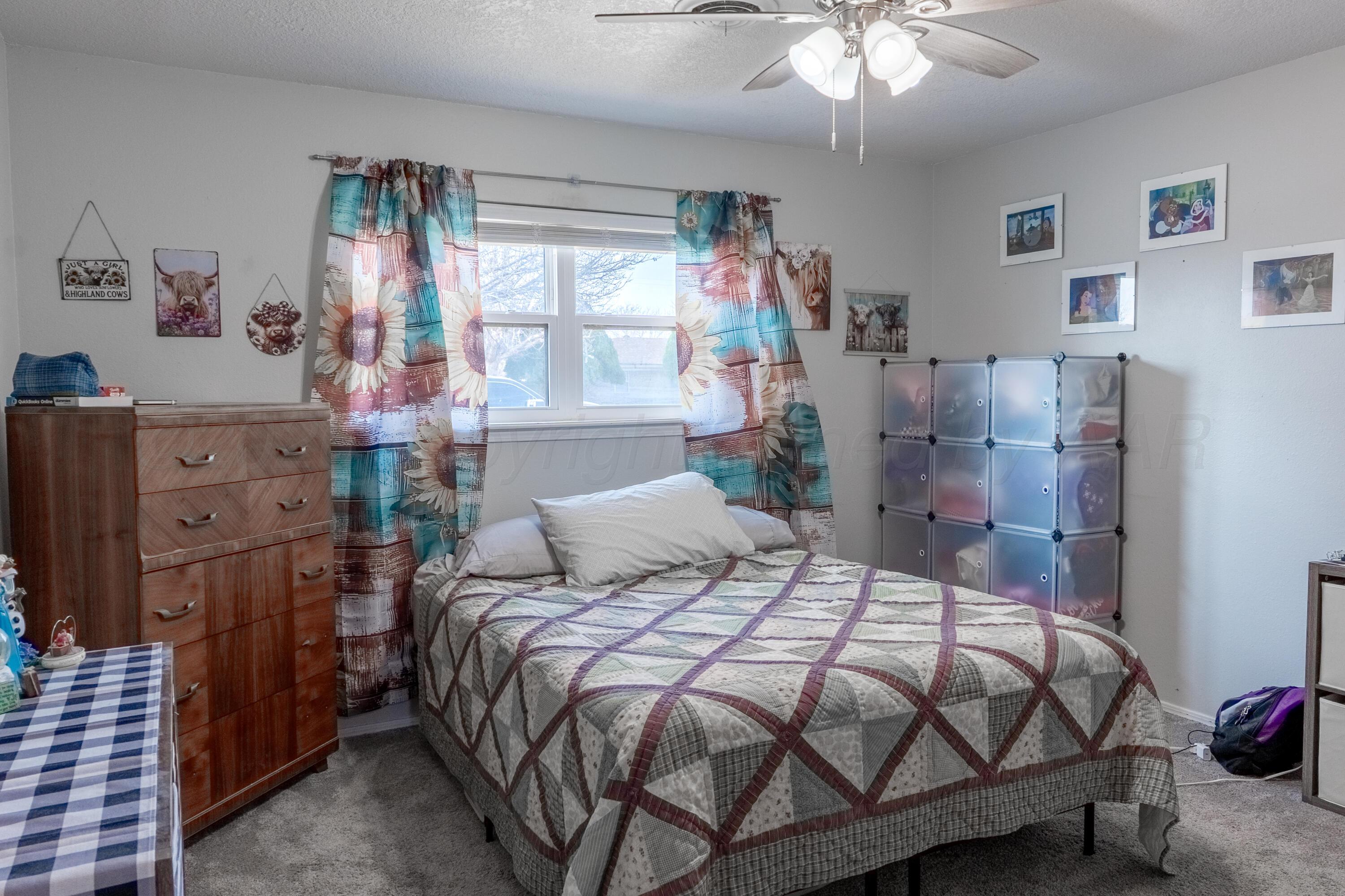 415 Mustang Street Fritch, TX 79036 - Photo 16 of 23 a bedroom with a bed and a chandelier