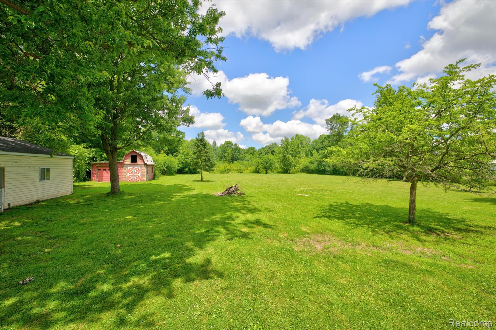 5244 Oleksyn Road Flint, MI 48504 - Photo 67 of 70 Expansive green lawn with mature trees and a classic red barn with white trim
