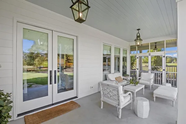 a dining room with furniture large windows and a chandelier