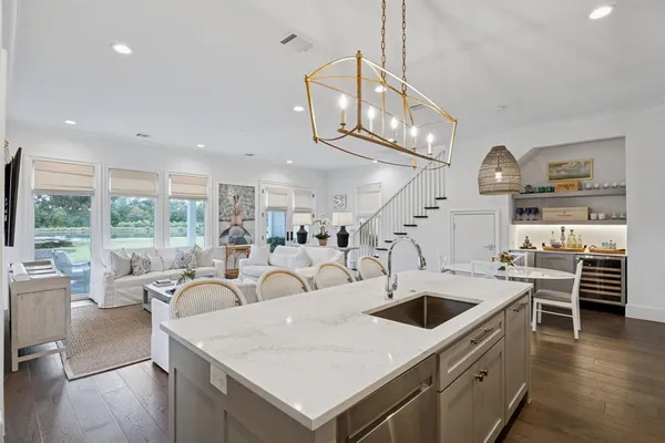 a large kitchen with stainless steel appliances kitchen island a large counter top a stove and a chandelier
